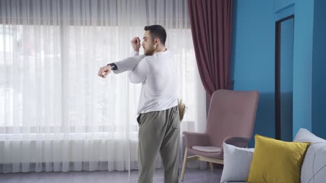 Young-athletic-man-doing-exercises-at-home-to-stretch-and-warm-up-his-arms-and-shoulders.